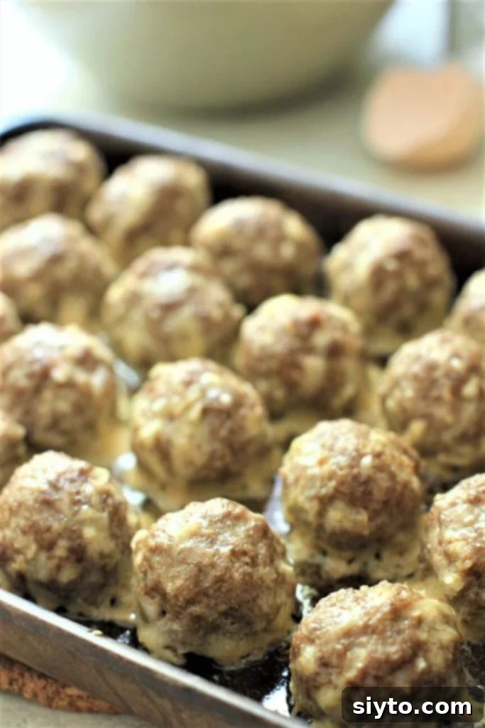 A baking pan filled with golden-brown baked meatballs, ready for sauce or serving.