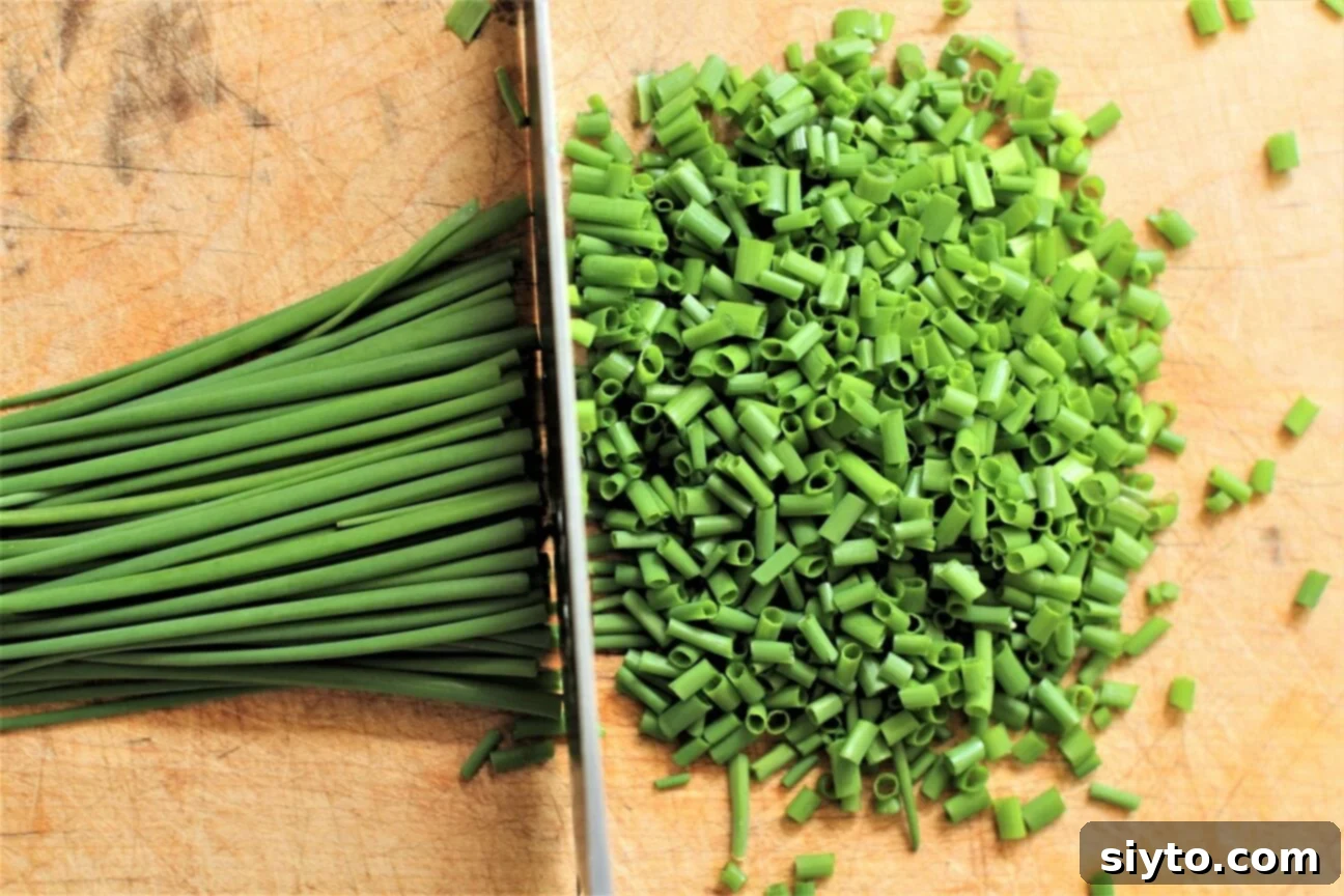 Chopping fresh chives on a wooden cutting board for the Chive & Egg Pasta Salad.