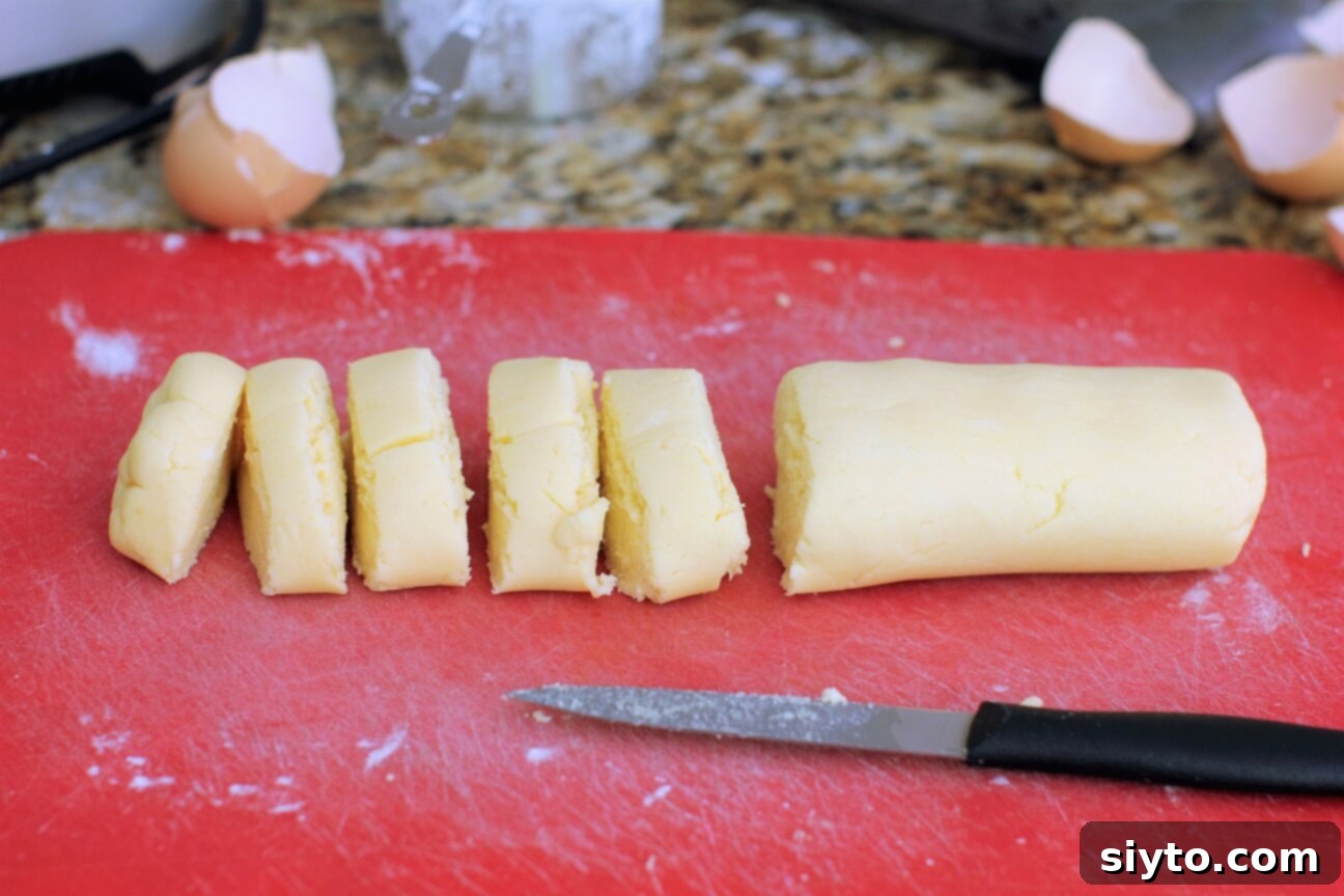 cutting the pan de yuca dough into equal portions, showing its soft, pliable texture like playdough