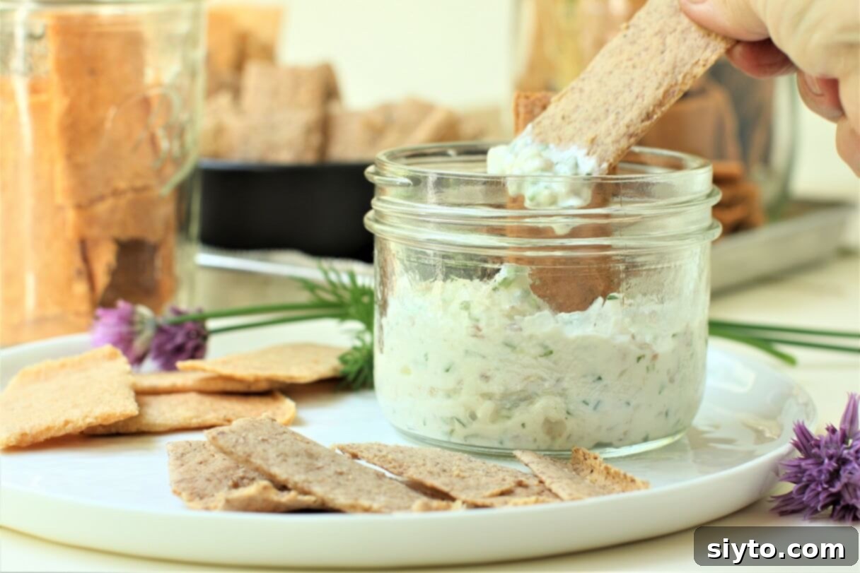 Artisan Gluten Free Sourdough Crackers 10 dipping the sourdough crackers into a jar of herb dip, highlighting their versatility