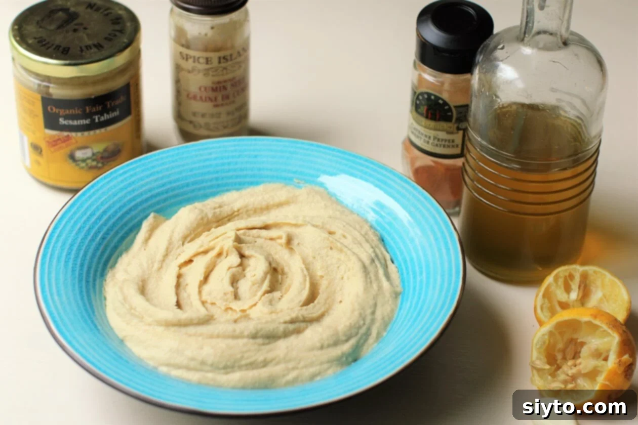 A simple, unadorned bowl of freshly made, perfectly smooth hummus, showcasing its natural texture before any garnishes are added.