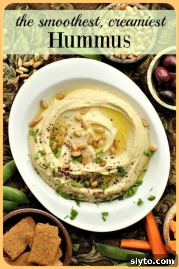 A close-up of incredibly creamy, dreamy homemade hummus in a beautiful bowl, lavishly garnished with a generous drizzle of olive oil, a sprinkle of sumac, toasted pine nuts, and fresh parsley for a stunning presentation.