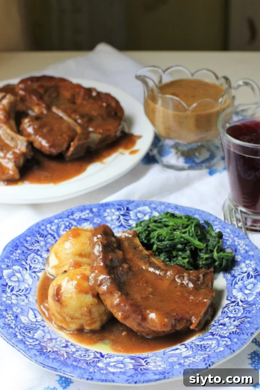 Southern Smothered Pork Chops: A Soul Food Classic 2 A plate of incredibly tender smothered pork chops in a rich onion gravy, served over mashed potatoes and alongside sautéed spinach, showcasing classic Soul Food comfort.