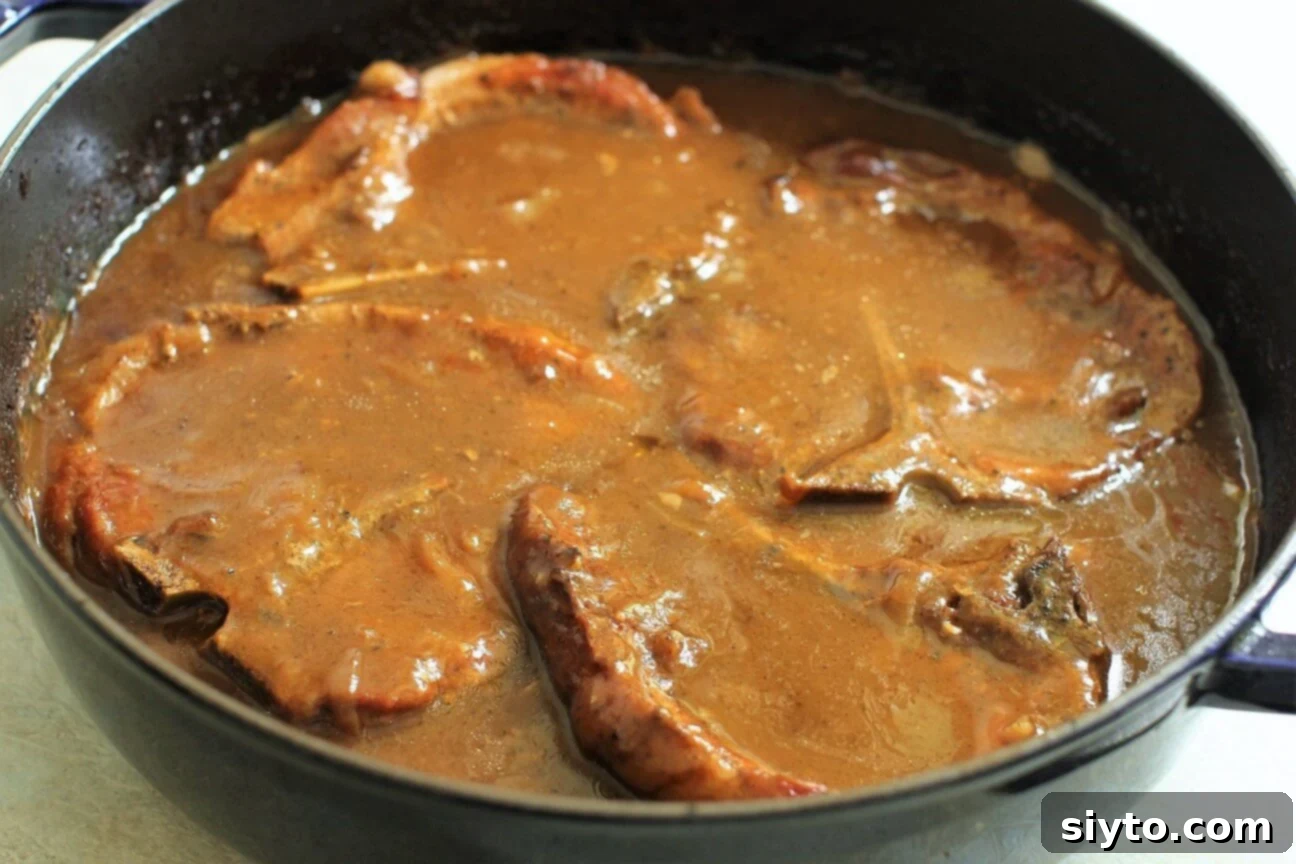 Southern Smothered Pork Chops: A Soul Food Classic 9 The fully cooked smothered pork chops, showcasing their incredible tenderness and a rich, thick, and flavorful gravy after a long, slow braise in the oven.