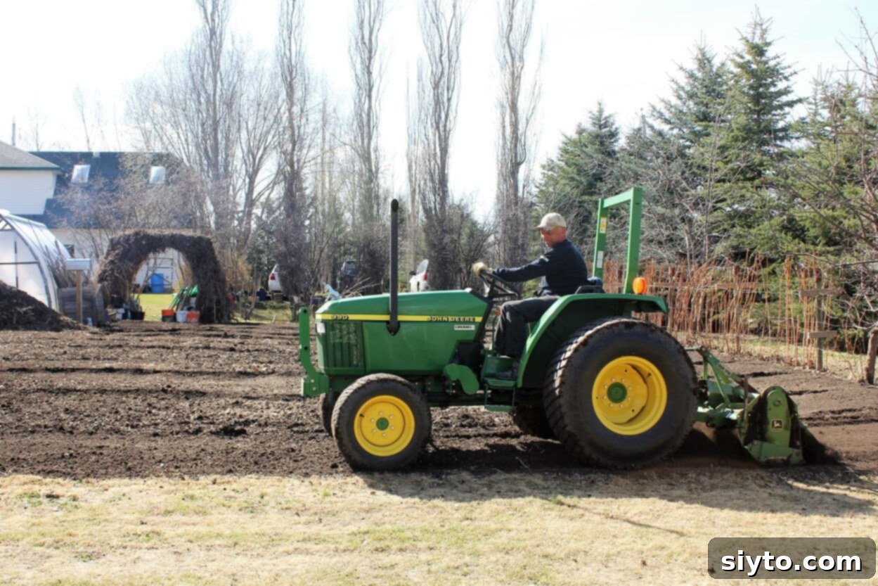 Ed skillfully driving his John Deere tractor, working the soil in our expansive garden on a bright day