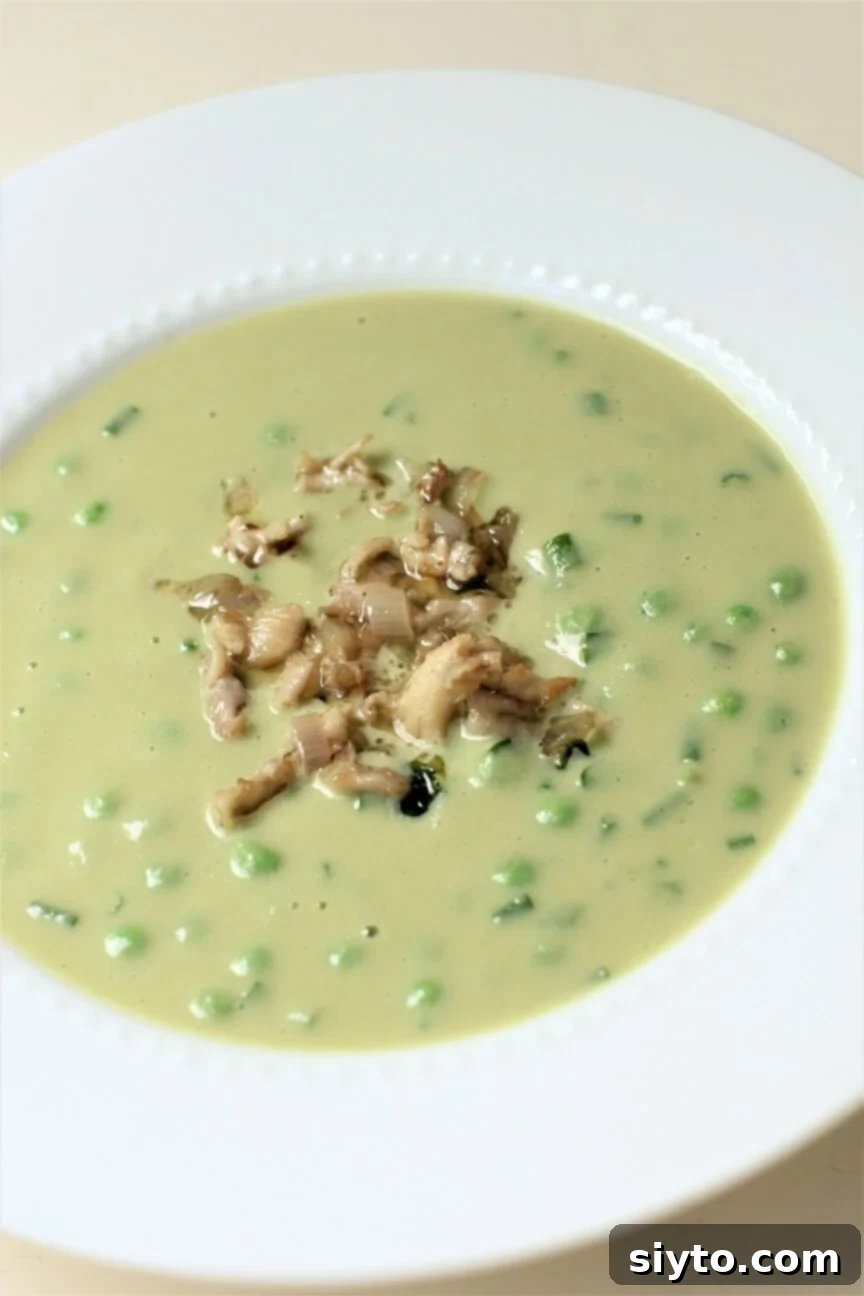 A spoonful of delicately sautéed Hericium coral mushrooms is perfectly placed atop a creamy bowl of pea and lettuce soup, adding an elegant garnish and unique texture.