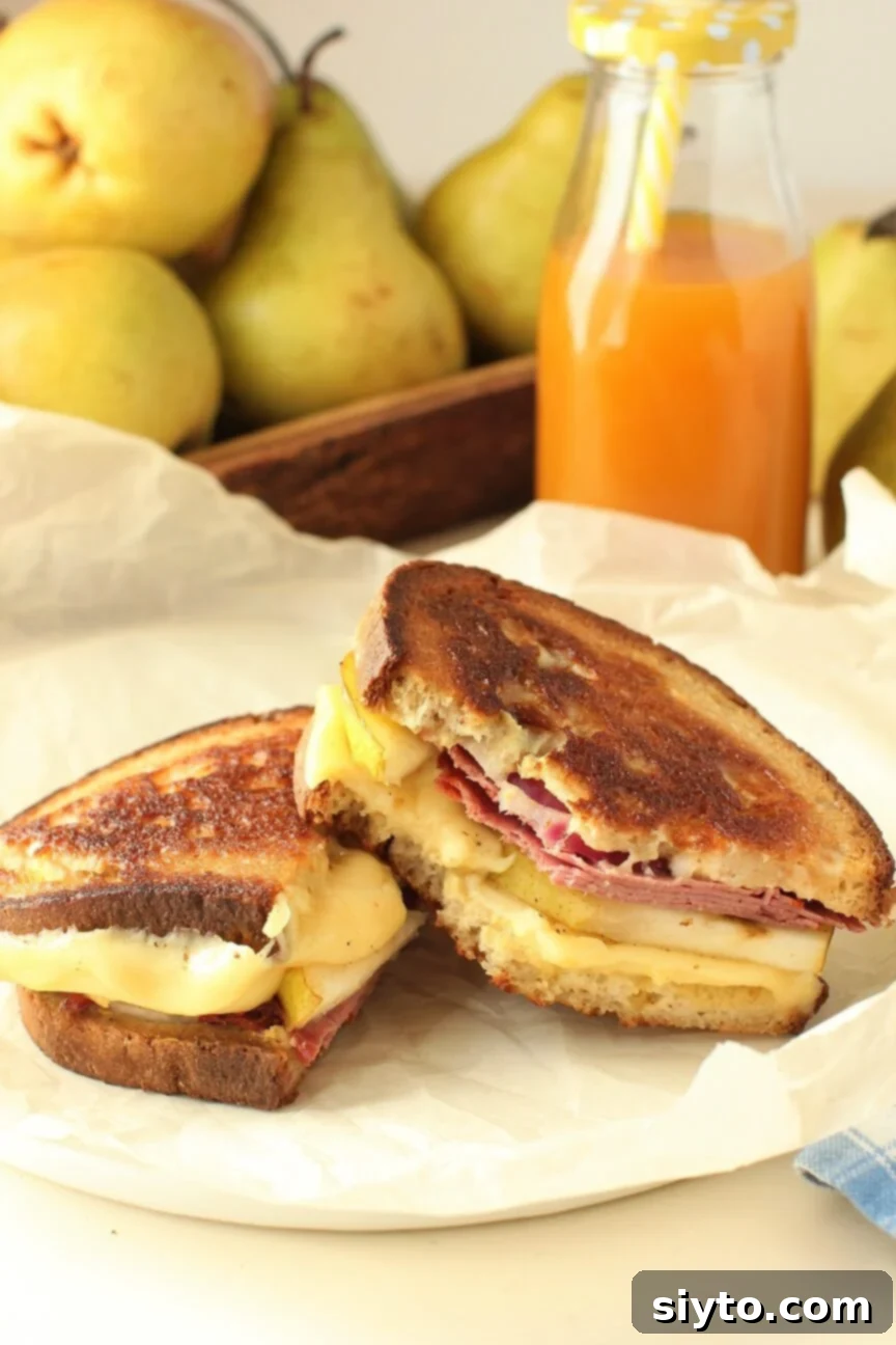 The ultimate gourmet grilled cheese with pastrami, fresh pear, and melted cheese, cut in half