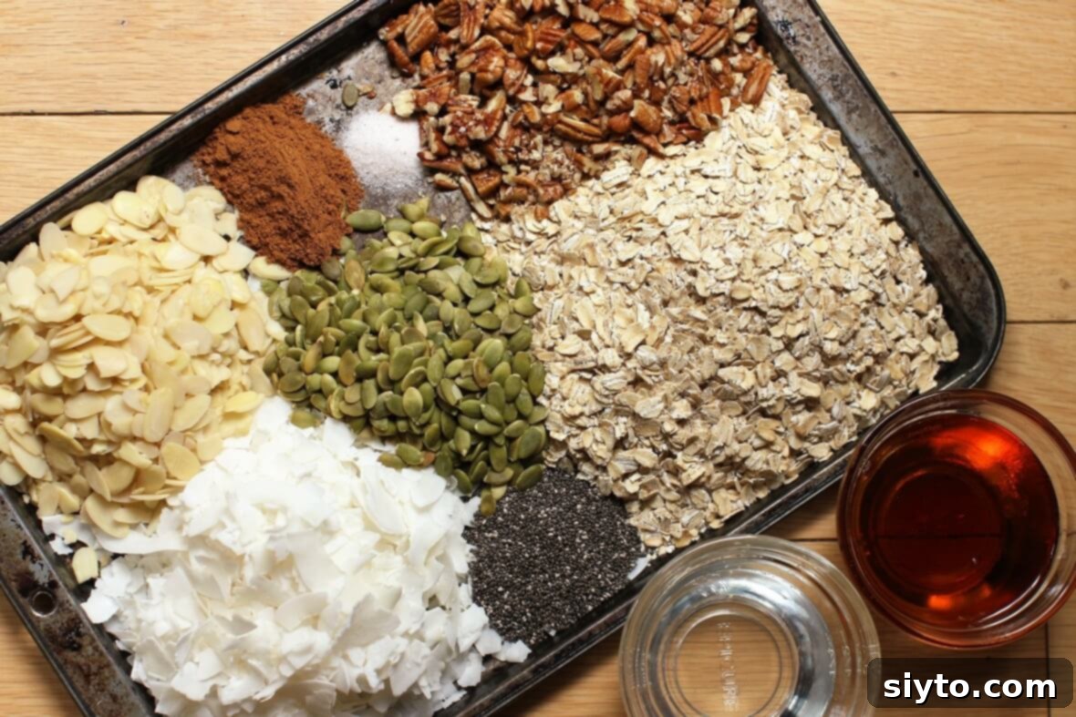 Piles of assorted dry ingredients for homemade granola laid out on a clean surface, including flaked coconut, rolled oats, pecans, pumpkin seeds, and sliced almonds.