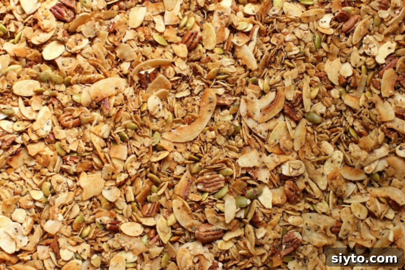 A close-up view of freshly baked, golden-brown granola cooling on a baking sheet, showing its rich texture and crispiness.