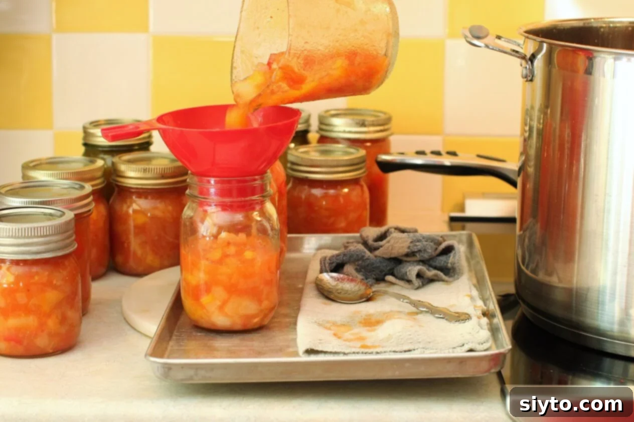 filling the canning jars with the cooked Peach Pear Chutney