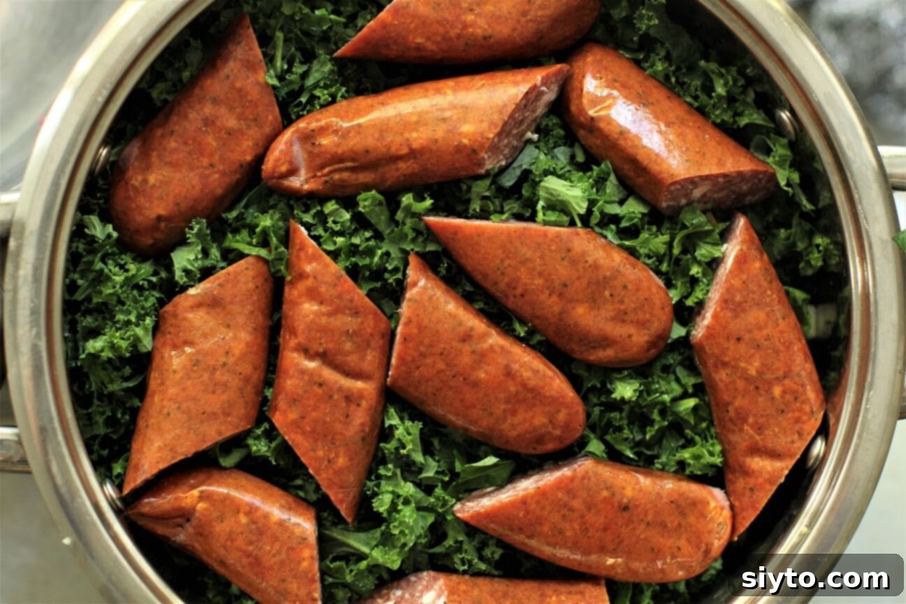 Boerenkool Stamppot The Heart of Dutch Comfort Food 8 Smoked sausage pieces carefully placed on top of finely chopped kale in a large cooking pot. Beneath are layers of potatoes and onions, demonstrating the efficient one-pot cooking method for Boerenkool Stamppot.