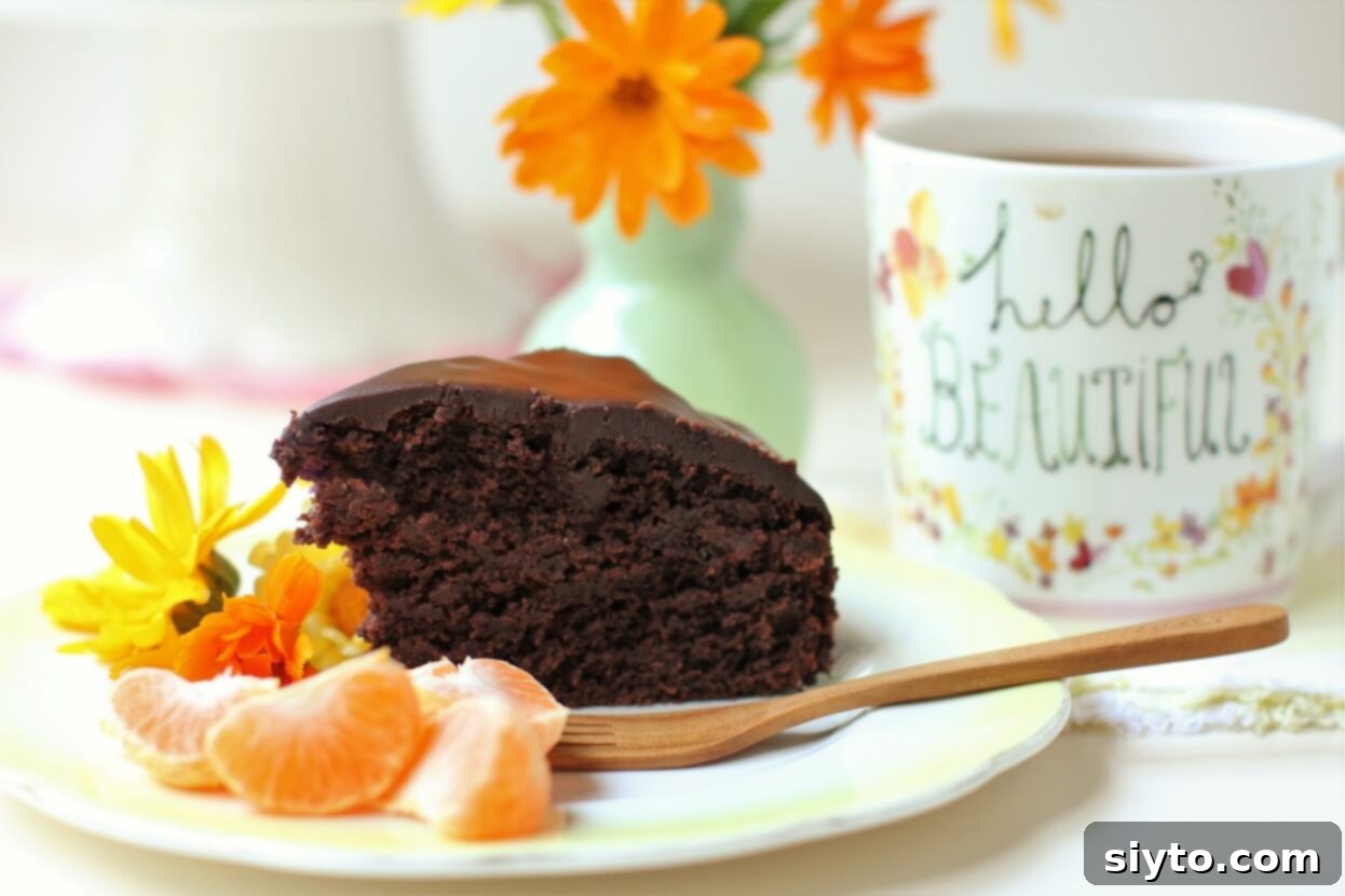 A generous slice of zucchini chocolate cake served alongside fresh orange slices and a coffee mug, creating an inviting breakfast scene