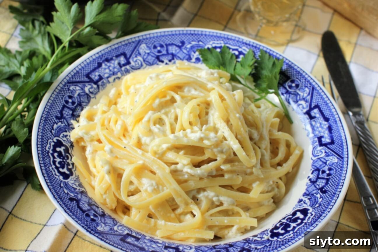A beautifully plated serving of puffball mushroom fettuccine alfredo in a blue willow pattern bowl