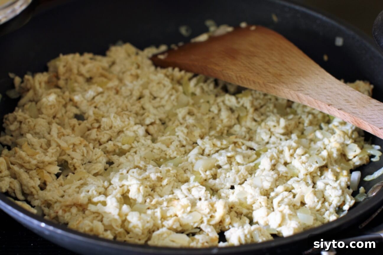 Cooking shredded giant puffball mushroom with diced onions in a large skillet until tender