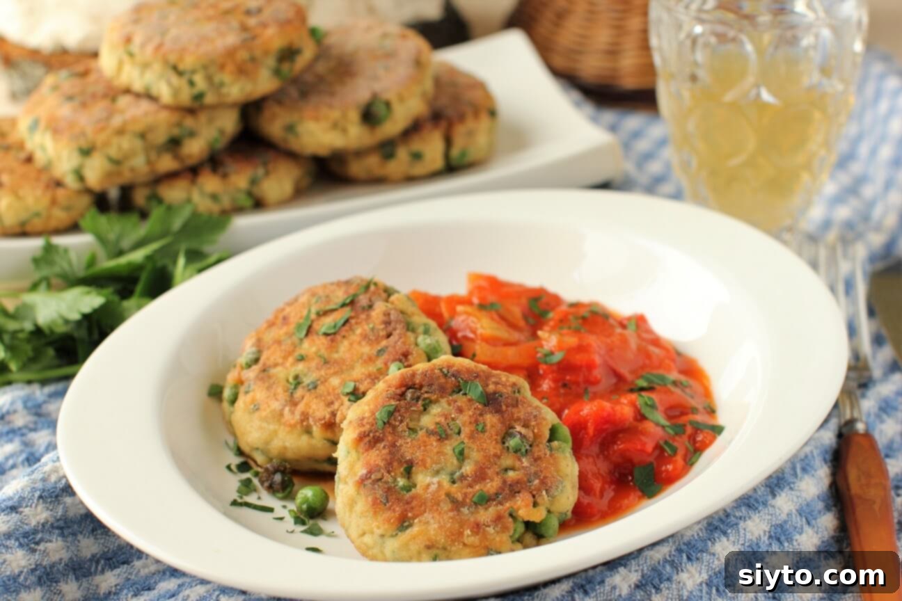 Two perfectly golden puffball patties arranged on a white plate with chunky cooked tomatoes, ready to be served.