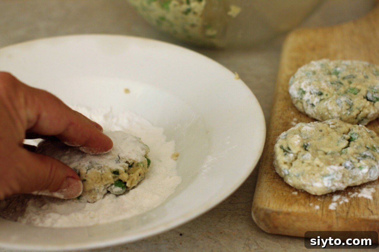 A puffball patty being dipped into a shallow bowl of flour, coating it evenly before frying.