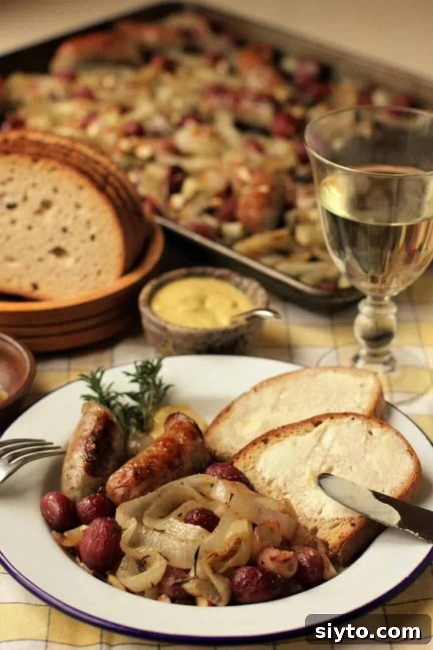 A beautifully plated Bratwurst Bake with Sweet Onions, Grapes, and Buttered Bread, accompanied by a wine glass. The sheet pan dinner is visible in the background, hinting at easy cleanup.