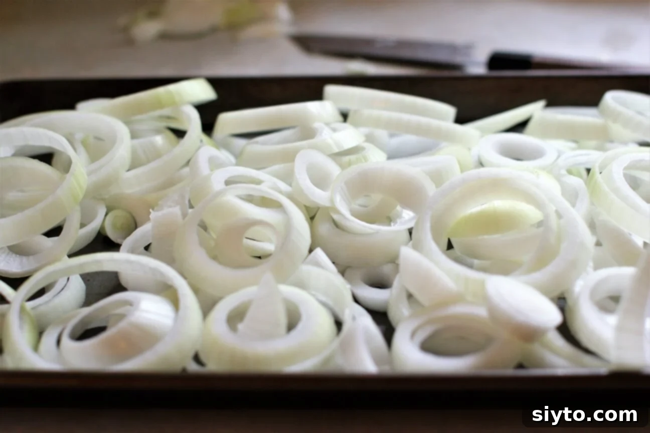 A sheet pan generously filled with vibrant Spanish sweet onion rings, perfectly prepared and ready to be seasoned and roasted.