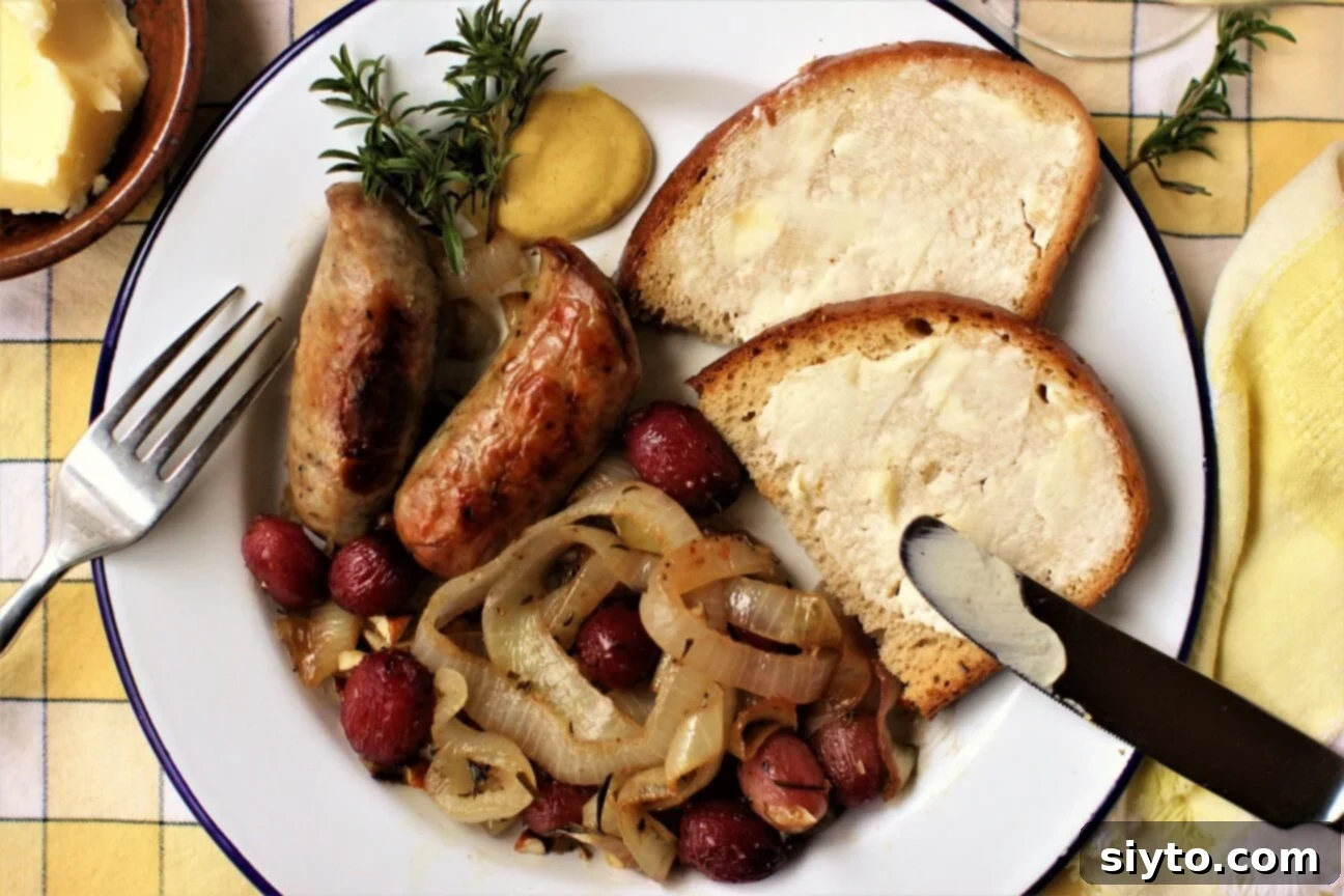 A delicious plate of Bratwurst Bake featuring roasted onions and grapes, served alongside a slice of buttered bread, inviting diners to indulge.