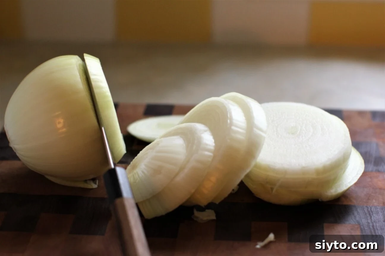 A close-up shot of slicing large Spanish sweet onions on a cutting board, showcasing their beautiful layers and readiness for cooking.