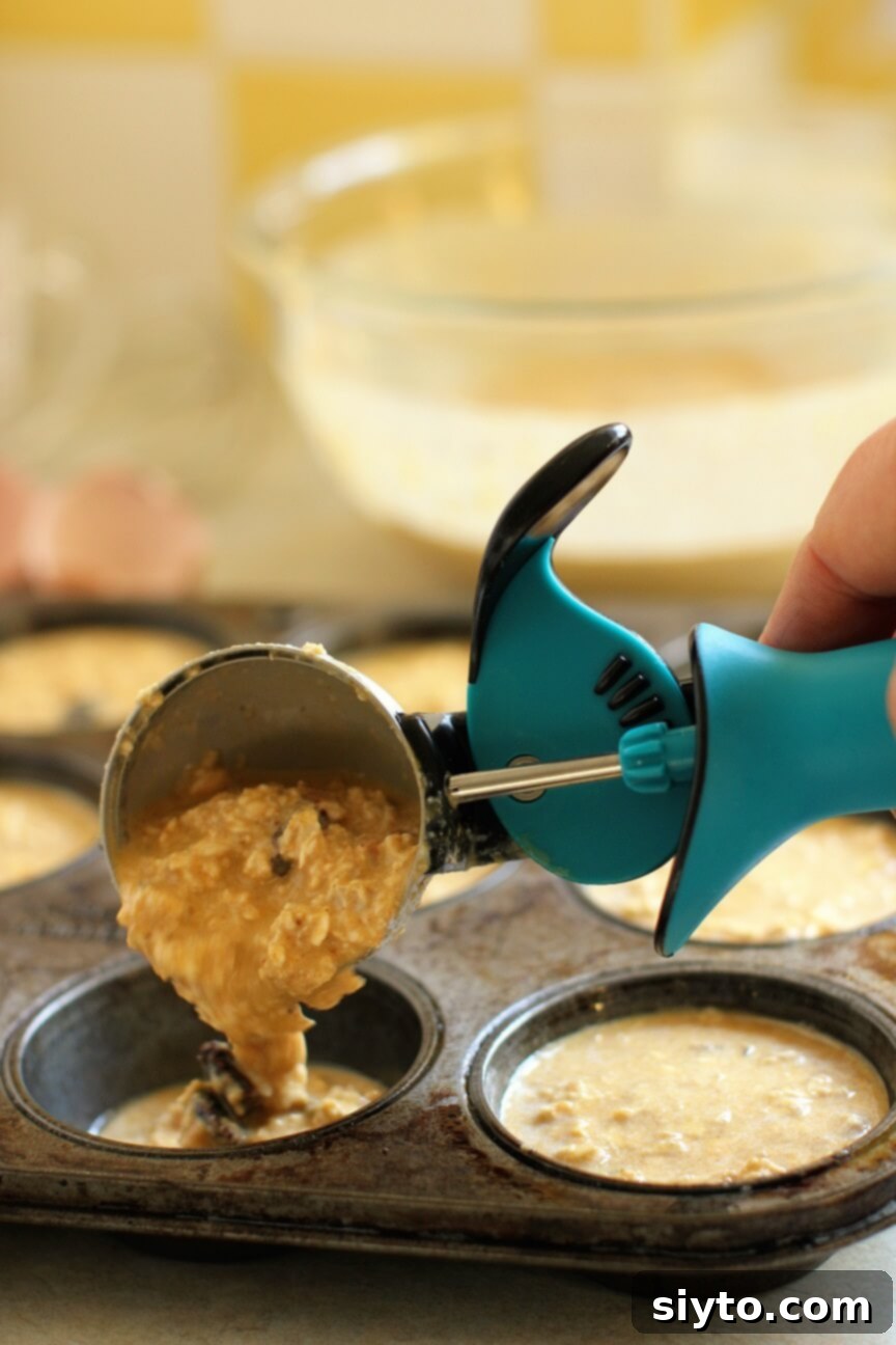 Handheld Harvest Pumpkin Oatmeal Muffins 4 scooping the batter into the muffin tins to bake