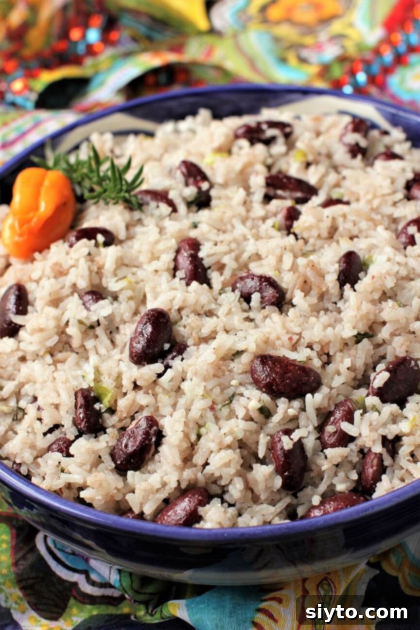 A vibrant bowl of authentic Jamaican Rice and Peas, showcasing fluffy coconut rice and tender red kidney beans, garnished with fresh herbs. Vertical view.