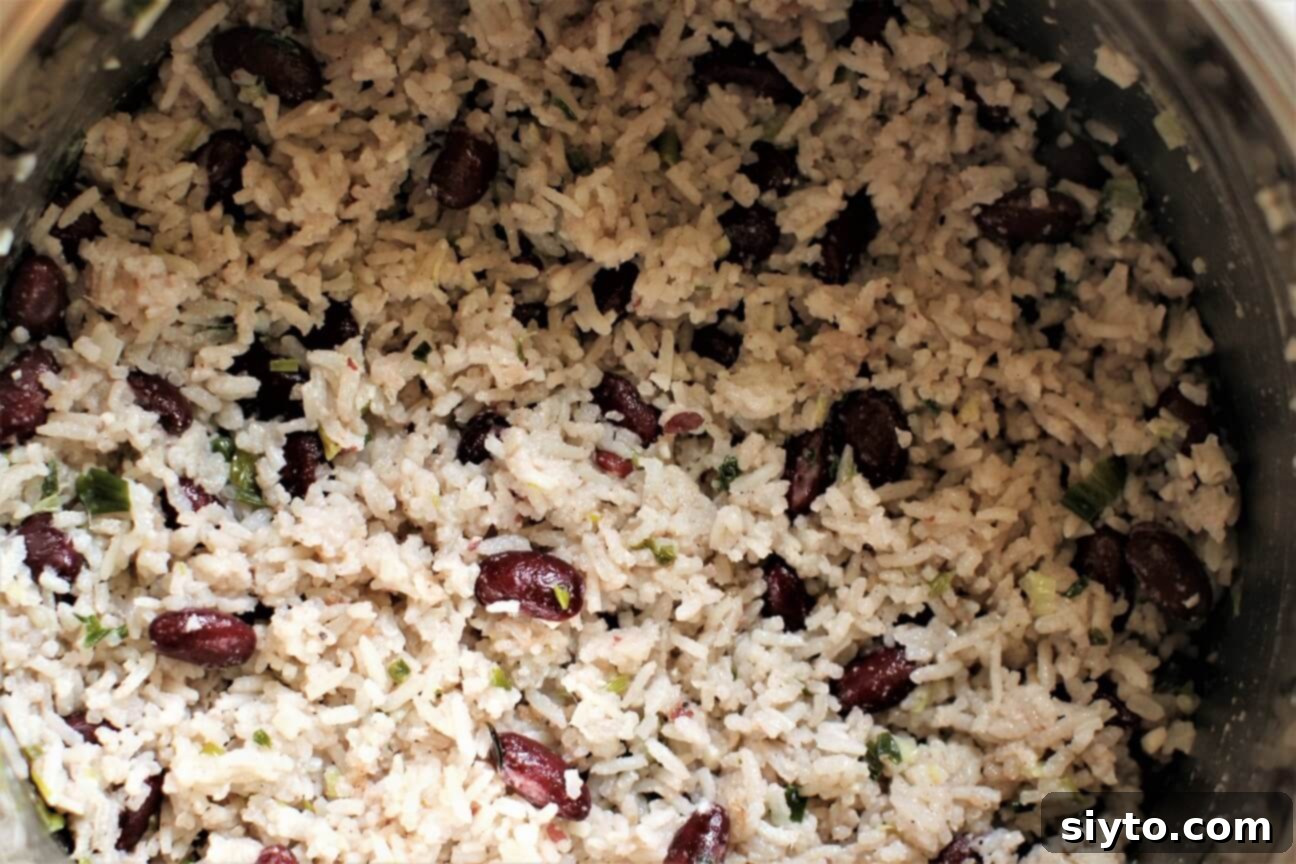 Close-up of perfectly fluffed Jamaican Rice and Peas in a pot, showing individual grains of rice and tender red beans.