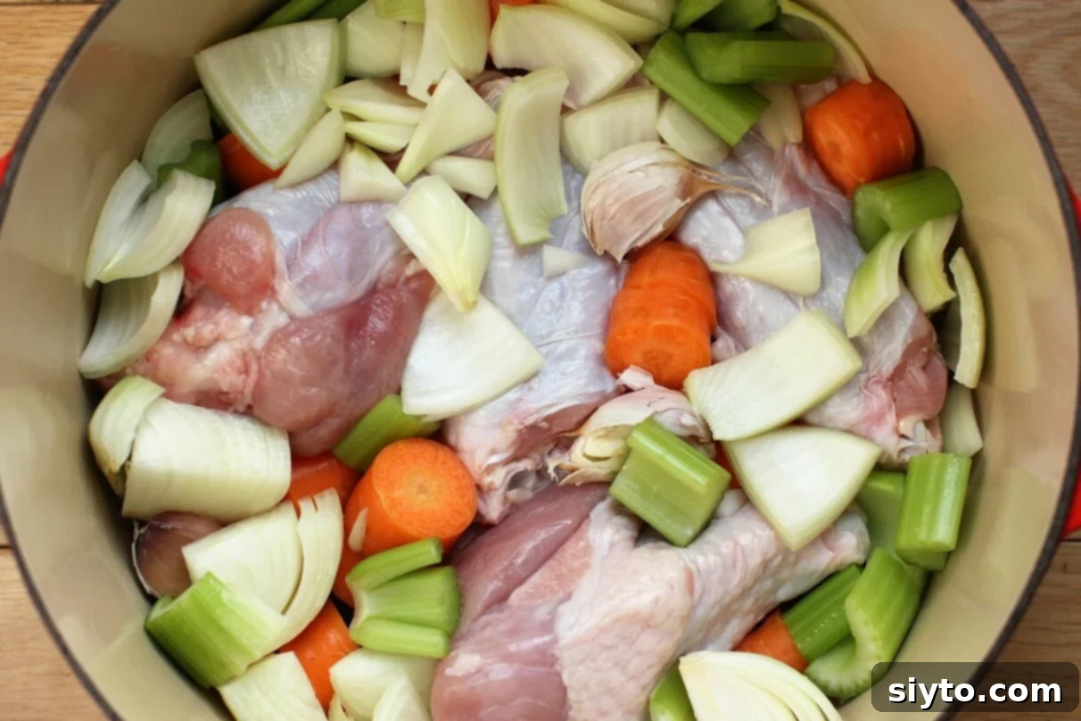 Turkey wings and chopped vegetables arranged in a roasting pot, ready for oven roasting to make flavorful gravy