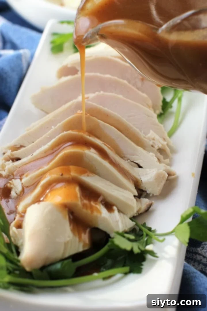 Sliced roasted turkey breast being drizzled with a generous serving of homemade gluten-free turkey gravy