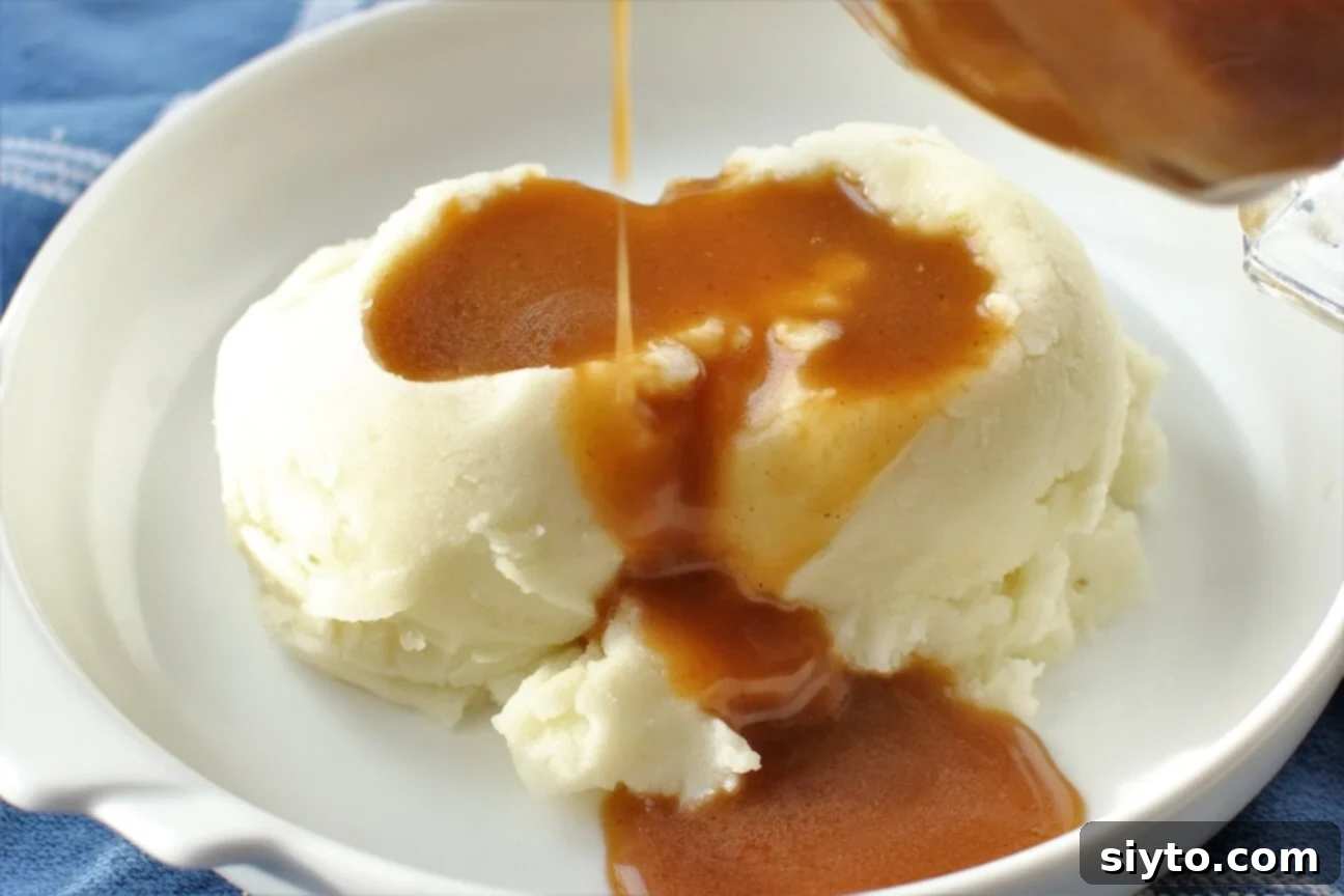 Horizontal shot of make-ahead gluten-free turkey gravy served generously over mashed potatoes