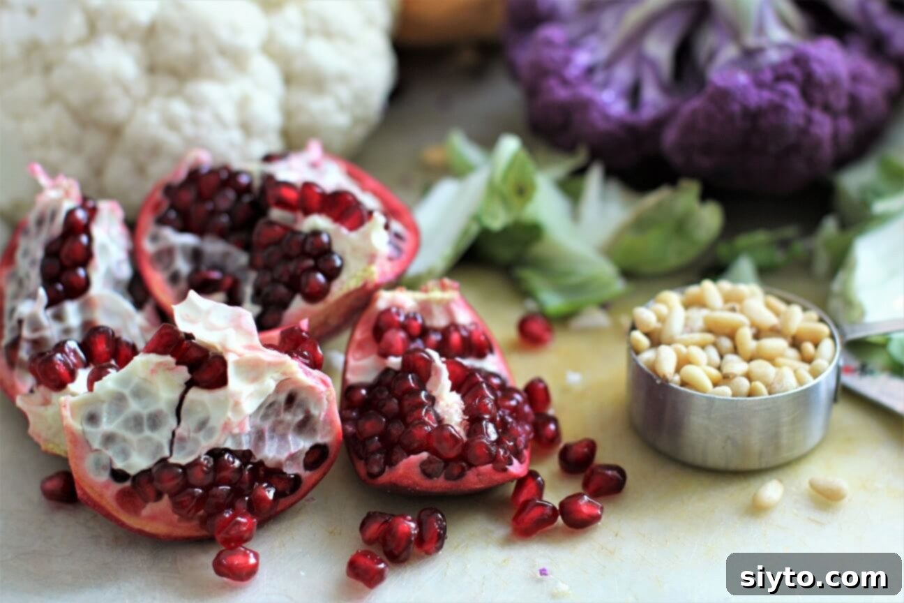 Close-up shot of vibrant pomegranate seeds and golden toasted pine nuts, ready to be sprinkled over the roasted cauliflower.