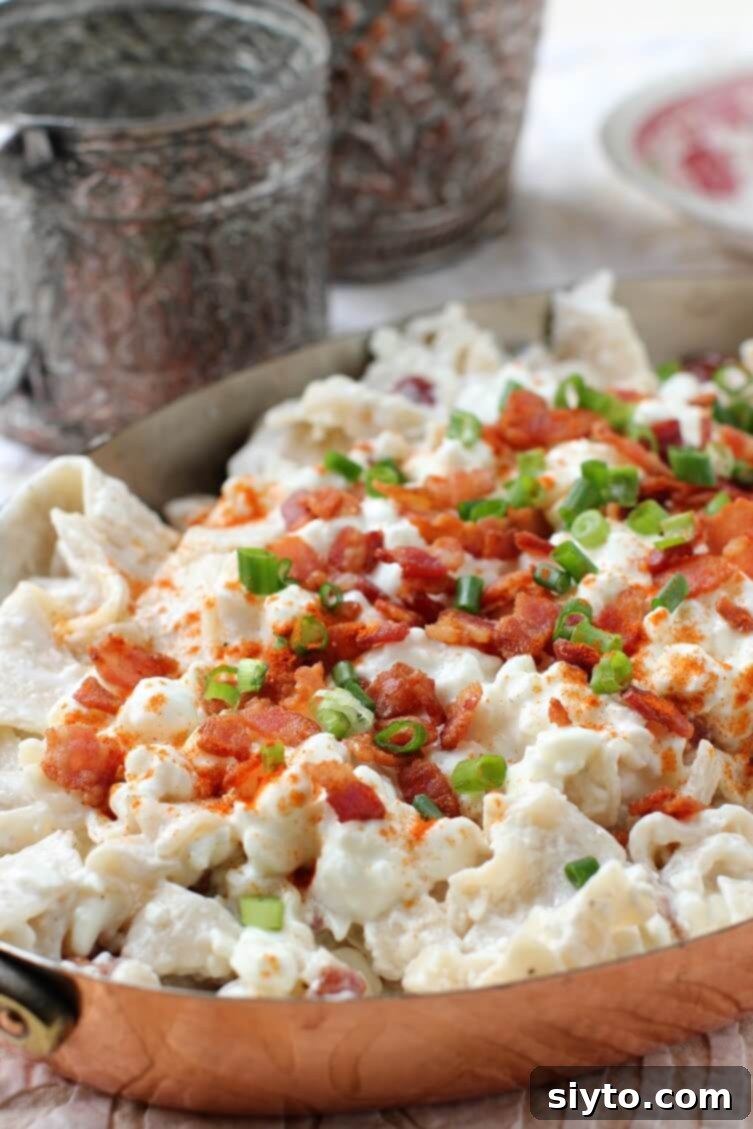 A rustic copper dish brimming with golden Túrós Csusza, showcasing the creamy pasta, cottage cheese, and crispy bacon bits.
