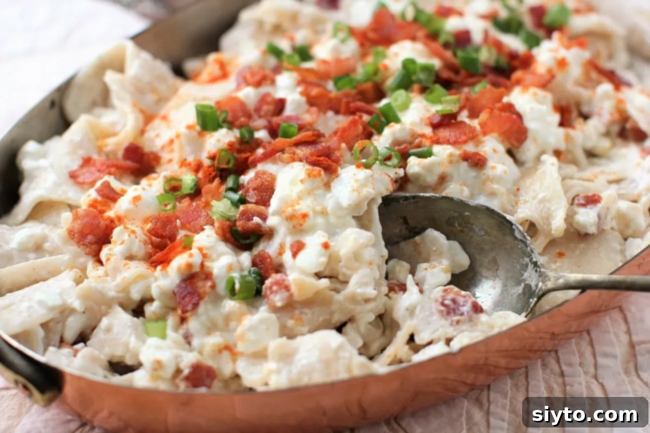 A spoonful of creamy Túrós Csusza being lifted from a white serving dish, highlighting the pasta, melting cottage cheese, and crispy bacon.