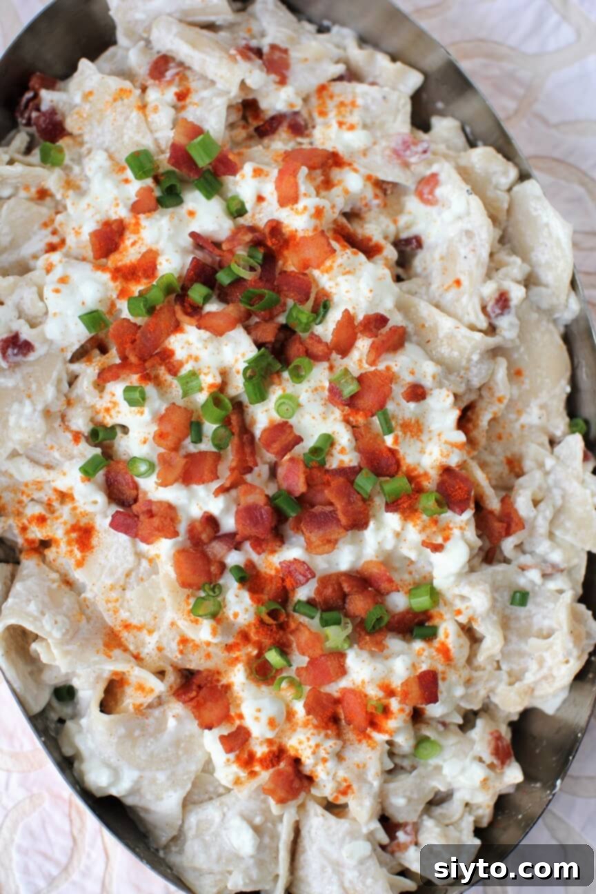 A top-down view of a serving of Túrós Csusza, garnished with crispy bacon and fresh green onions, inviting a delicious meal.
