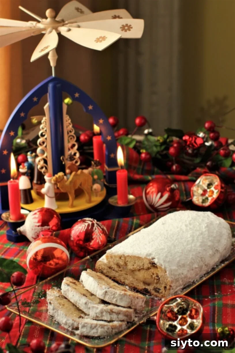 Quarkstollen: The Quicker German Christmas Cake 2 German Christmas Stollen sliced on a plate in front of a Weihnachtspyrimide