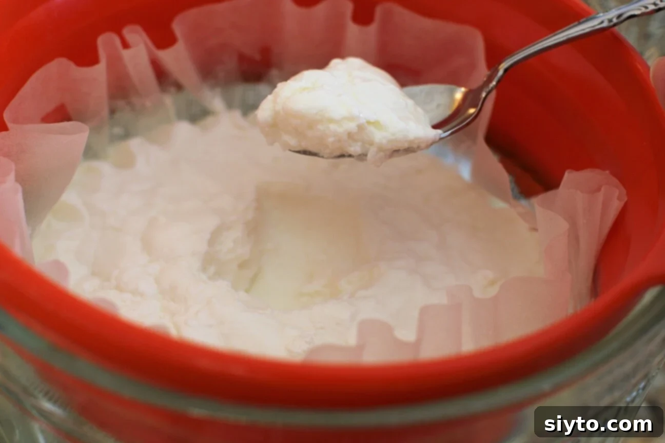 Quarkstollen: The Quicker German Christmas Cake 5 scooping a spoonful of the strained yogurt