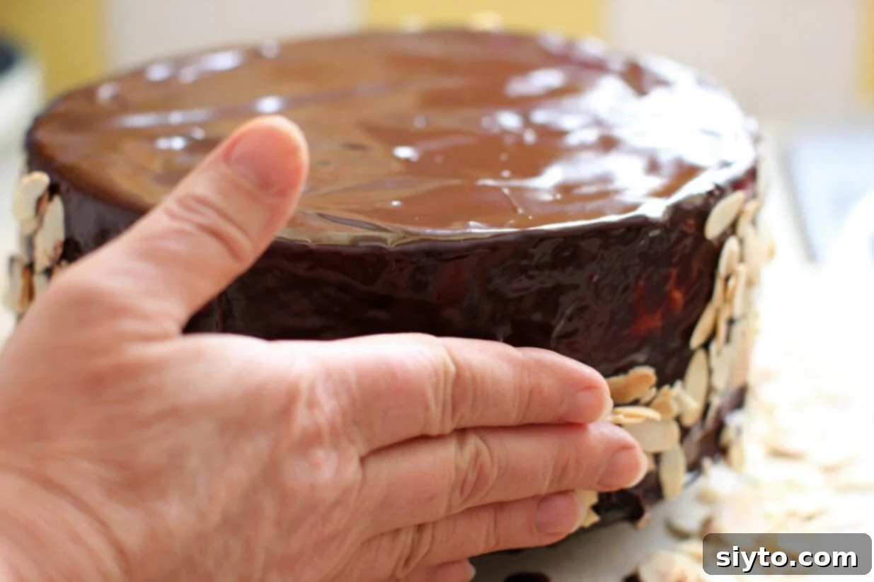 adding handfuls of sliced almonds to the sides of the glazed cake