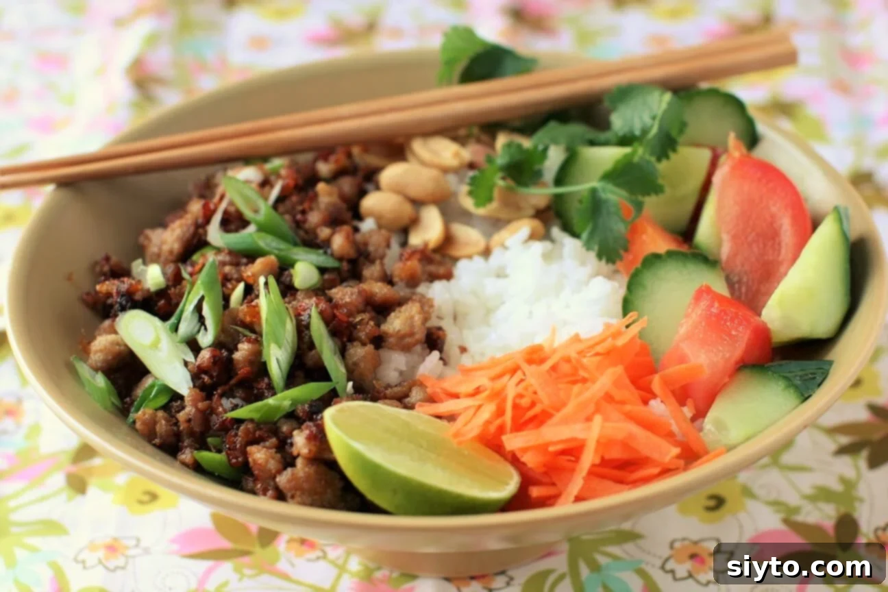Vietnamese rice bowl with sweet spicy ground pork, peanuts, fresh veggies, a complete and flavorful meal