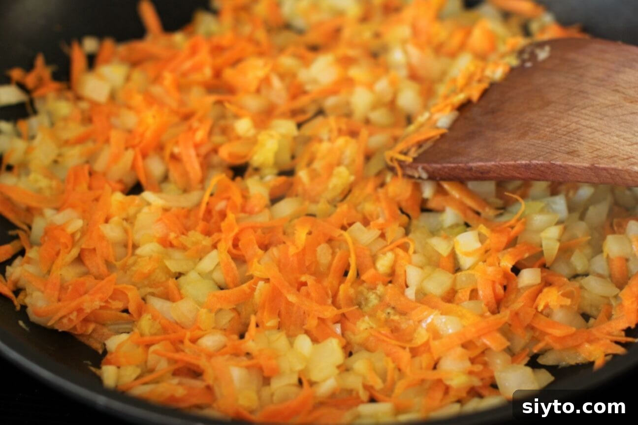 Skillet with onions and carrots being sauteed, releasing their aroma