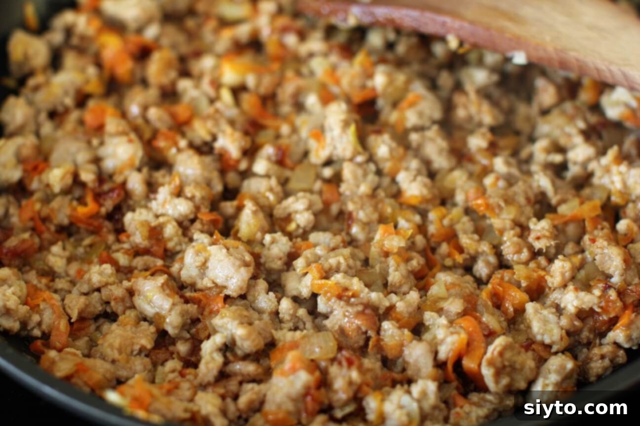 Cooked ground pork, simmering, still needs more caramelization to achieve crispy bits