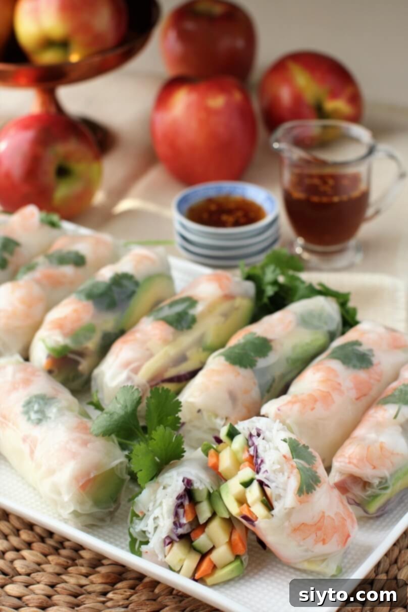 A collection of apple and shrimp summer rolls arranged artfully on a plate, with a background of fresh Cosmic Crisp apples, highlighting the star ingredient.