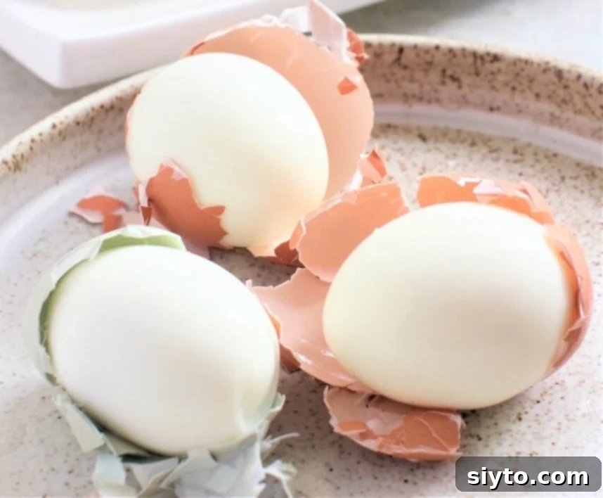 3 partially peeled eggs on a plate