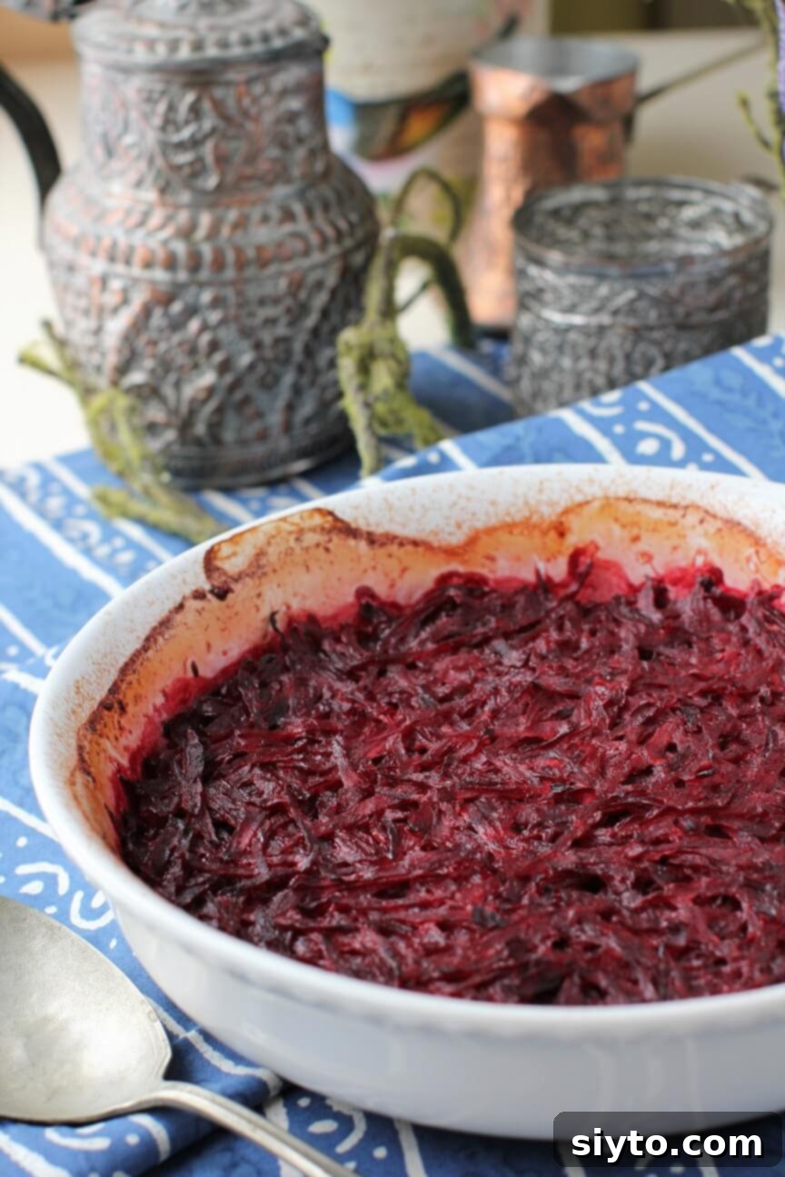 A close-up of a white baking dish filled with creamy, shredded baked beets, showcasing their rich ruby color and tender texture.