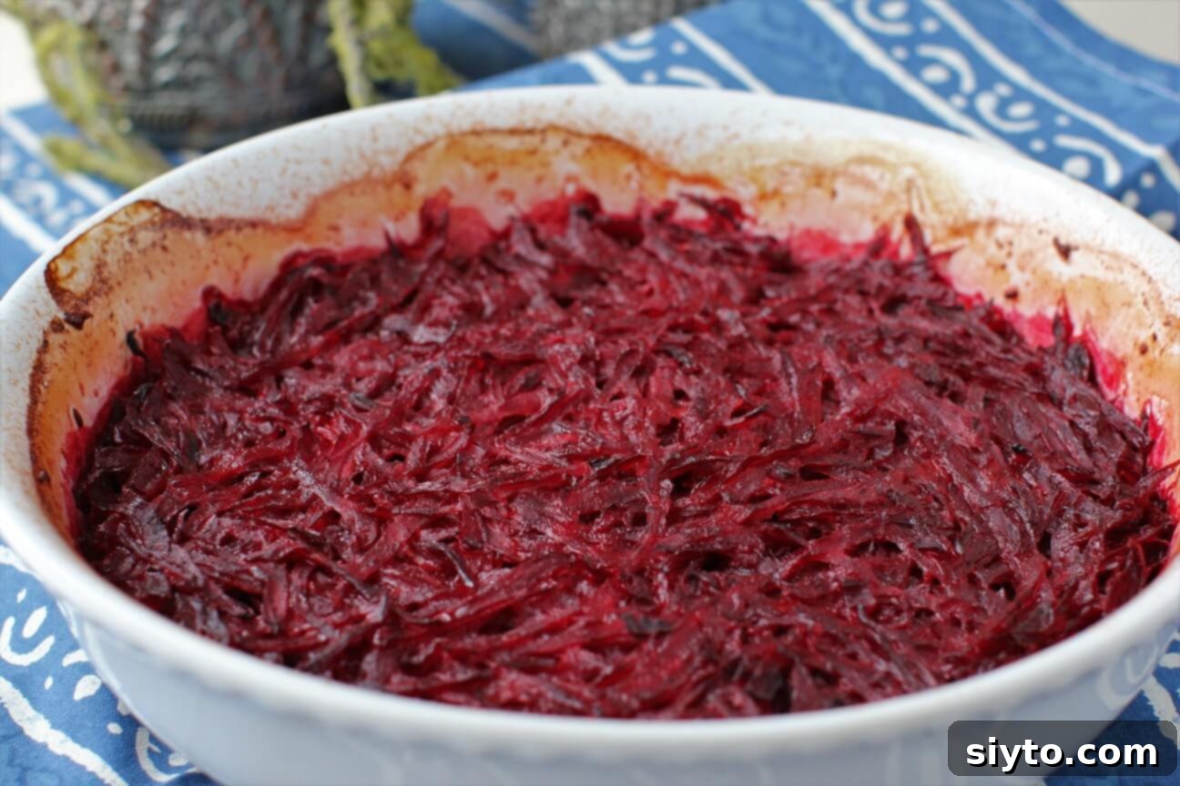 A hot roasting dish of ruby red beet gratin, fresh out of the oven, steaming and ready to be served as a comforting side dish.