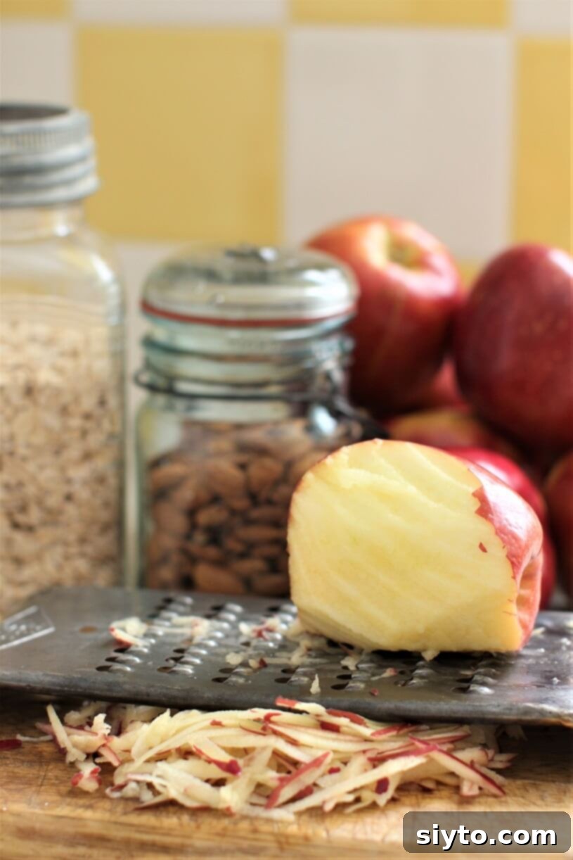 freshly grated apple, the grater, jars of oats and almonds, vertical