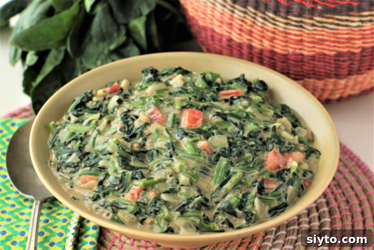 yellow bowl of peanut creamed spinach with tomatoes, ready to serve