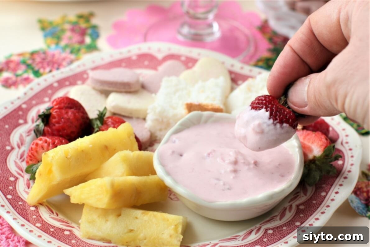 dipping a strawberry into the pink fluff