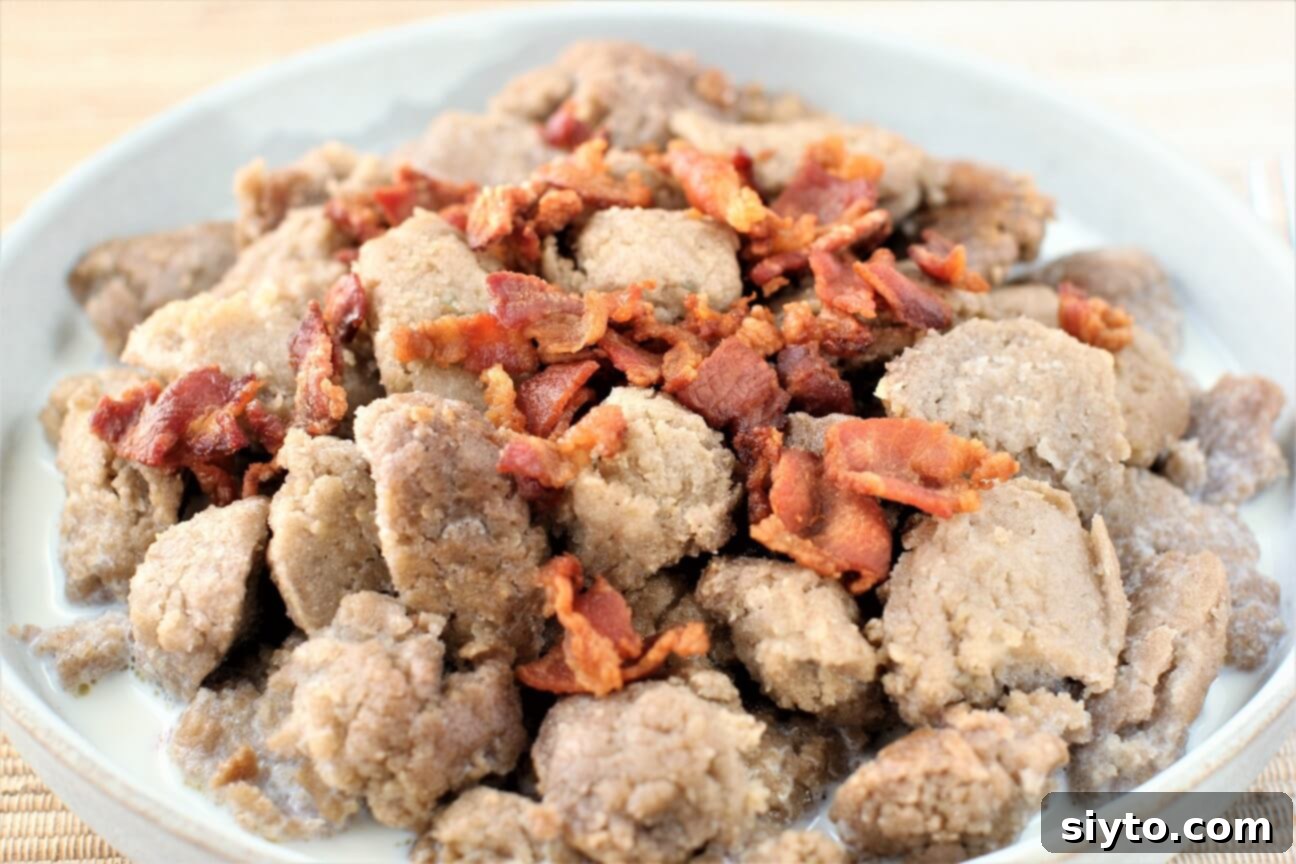 Close-up shot of buckwheat dumplings served in a flat bowl, garnished with crispy bacon and a pour of milk, ready to be enjoyed.