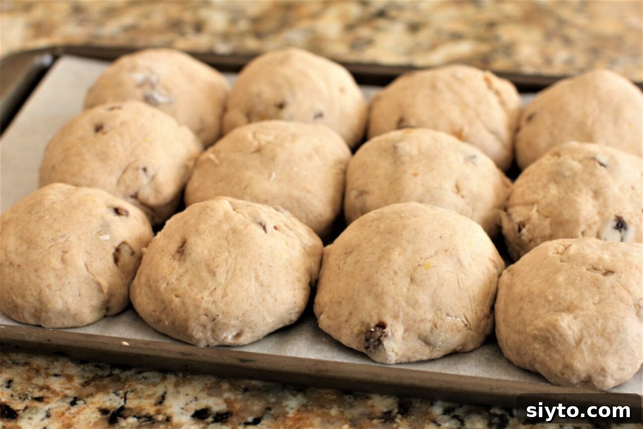 Fluffy Gluten-Free Hot Cross Buns 9 Shaped gluten-free hot cross buns arranged on a baking pan, touching each other for optimal rising