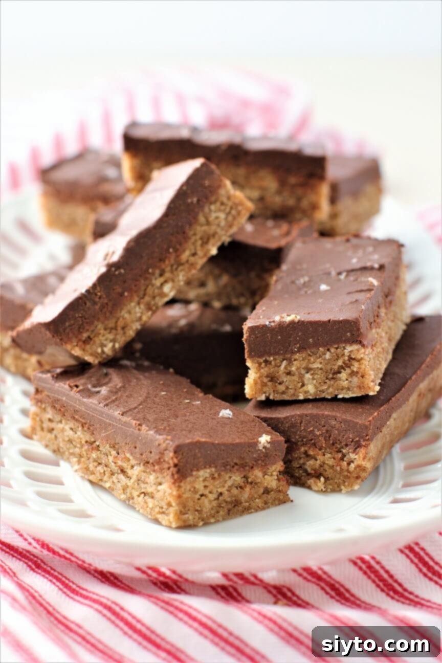 Pile of rich, fudgy No-Bake Chewy Chocolate Almond Bars on a pristine white plate, showcasing their delightful texture and two-layer structure.
